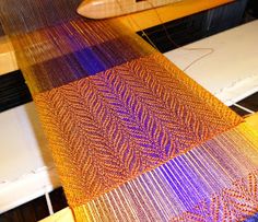 an orange and purple piece of cloth on top of a table next to a sewing machine