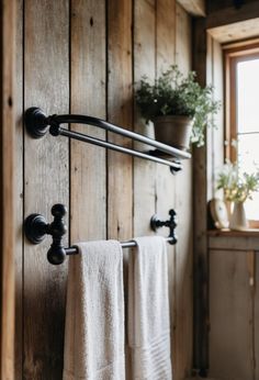 two towels hanging on the wall next to a window with potted plants in it