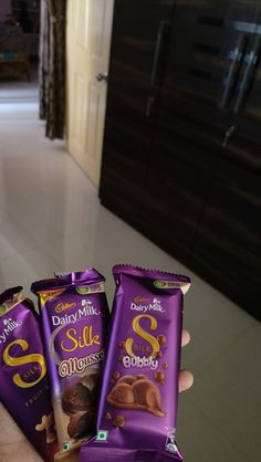 three bags of dairy milk chocolates in someone's hand