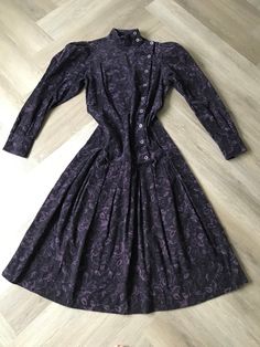 "So good! Rare gem of a vintage 1980s Laura Ashley dress made in Great Britain. Rich purple floral patterned soft pinwale corduroy. Asymmetrical side button front with puffed long sleeve and high neck; dropped waist with box pleats; princess seams at back for nice fit; two-button sleeve cuffs. Simply an extraordinary dress in excellent condition. Photographed on a size 8 form US size 10 / UK size 12 Measures  Bust: 36\" Torso/ Waist: 34\" Hips/ Drop Waist : 40\"" Vintage Long Sleeve Dresses With Covered Buttons, Retro Vintage Long Sleeve Dress With Buttons, Retro Long Sleeve Vintage Dress With Buttons, Long Sleeve Vintage Dress With Buttons For Fall, Formal Vintage Dress With Buttons For Fall, Fall Vintage Long Sleeve Dress With Buttons, Long Sleeve Vintage Dress For Formal Fall Events, Formal Vintage Long Sleeve Dress For Fall, Formal Long Sleeve Vintage Dress