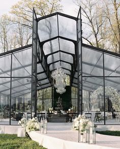 the inside of a large glass building with tables and chairs set up for an event