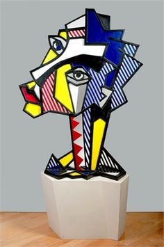 a colorful sculpture is sitting on a wooden table in front of a gray wall and wood floor