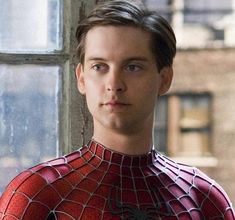 the amazing spider - man is looking at the camera while standing in front of a window