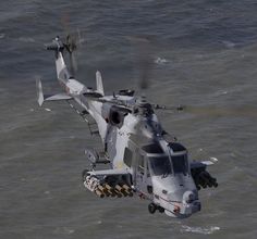 a helicopter flying over the ocean with propellers on it's wings and landing gear