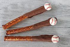 three baseball pretzel rods with chocolate and nuts on them sitting on a wooden table