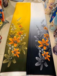 two table runners with flowers painted on them in yellow and black colors, sitting next to each other