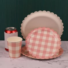 a table topped with plates and cups next to a can