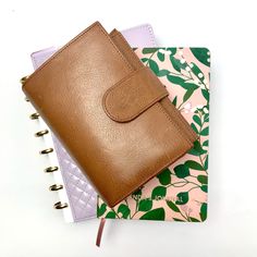 a brown leather wallet sitting on top of a notebook