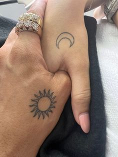 two people holding hands with sun and moon tattoos on their fingers, one has a diamond ring in the other hand