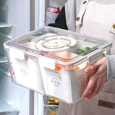 a person holding a plastic container with food in it and an open refrigerator door behind them