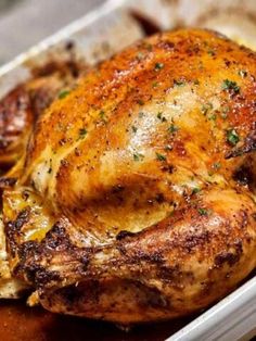 a roasted chicken in a baking dish with herbs