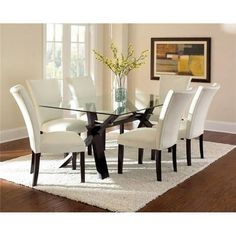 a glass dining table with white chairs around it