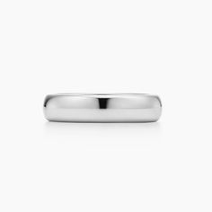 a wedding band in white gold on a plain surface with a slight, rounded edge