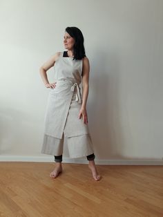 a woman standing in front of a white wall with her hands on her hips wearing a gray dress