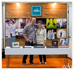 two people standing next to each other in front of a table with pictures on it