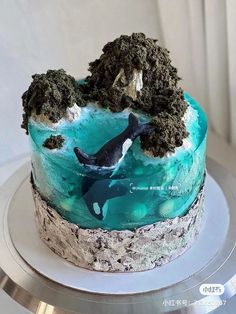 a blue and white cake with an orca in the ocean on it's side