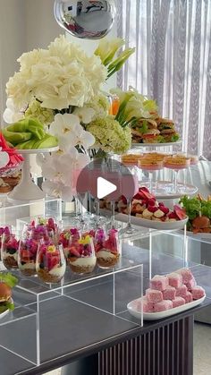 a table topped with lots of desserts and flowers on top of glass containers filled with food