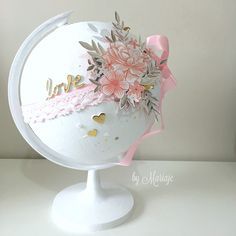 a white globe with pink flowers on it and the word love is written in gold