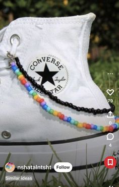 a pair of white converse sneakers with colorful beads on the bottom and black laces