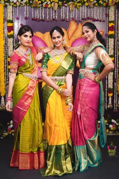 three women standing next to each other in colorful sari