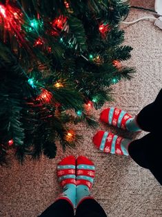 two people wearing red and blue striped shoes next to a christmas tree