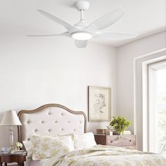 a bedroom with a white ceiling fan and floral comforter on the bedspread