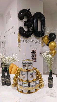 a table topped with lots of bottles of beer next to balloons in the shape of numbers