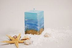 a blue candle sitting on top of snow next to starfish