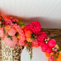 an arrangement of balloons, flowers and other decorations on a table in front of a wall