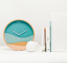 a clock sitting next to a book on a table