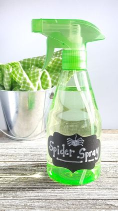 a bottle of spider spray sitting on top of a wooden table next to a metal bucket