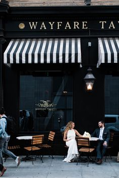 a man and woman sitting at a table in front of a restaurant