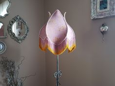 a pink lamp sitting on top of a table next to a mirror and framed pictures