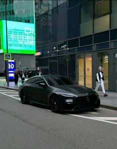 a black sports car parked on the side of a road next to a tall building