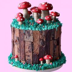 a cake decorated with mushrooms and grass on a stand against a pink background, in the shape of a log