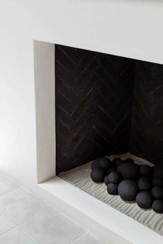 a white fireplace with black rocks in the middle