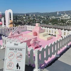 a pink and white play set on top of a building with a teddy bear in the background