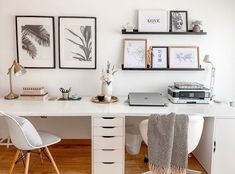 a white desk with two chairs and pictures on the wall above it in a home office