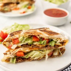 a white plate topped with a cut in half quesadilla and lettuce