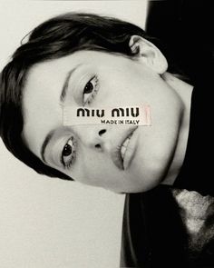 a black and white photo of a young woman with an ad taped to her face