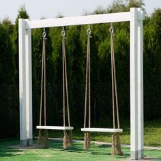 two white benches sitting next to each other on top of a grass covered park bench