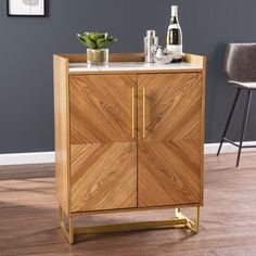 a wooden cabinet with two doors and some plants on top of it in front of a gray wall