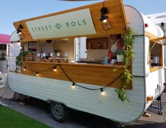 a food truck is parked on the side of the road with lights hanging from it's roof