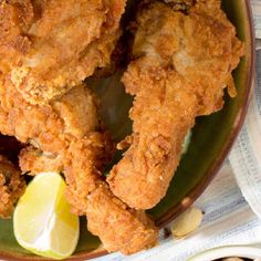 fried chicken on a green plate with lemon wedges and a side of breadcrumbs