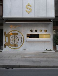 a white building with gold accents on the front and side windows, along with a sign that reads $