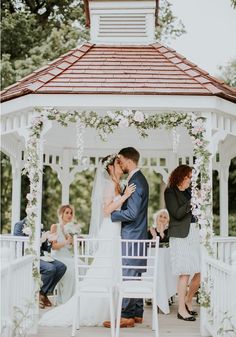 a bride and groom kissing in front of a gazebo at their outdoor wedding ceremony