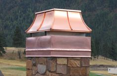 a copper chimney on top of a stone wall