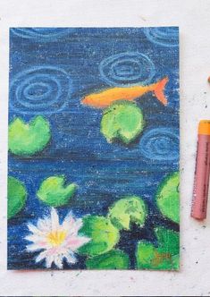 a painting with water lilies and a goldfish in the pond next to some crayons