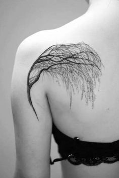 the back of a woman's shoulder is covered with branches and leaves, as well as her bra