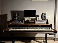 an electronic keyboard sitting on top of a wooden table next to a monitor and speakers